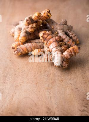turmeric roots, traditional southeast asian spice on a wooden table top, also known for medicinal purposes, taken in shallow depth of field Stock Photo