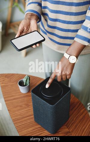 Vertical close up of African American woman using smart speaker in modern home Stock Photo