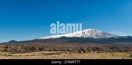 A view of Mount Etna (3357m) in late winter, seen from the town of Bronte on its western side. It is one of the most active volcanoes in the world. Stock Photo