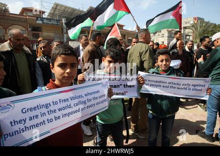 Rafah, Gaza. 07th Mar, 2022. Young Palestinian boys lift placards during a rally demanding international support for Palestinians against Israel at the Rafah refugee camp in the Gaza Strip on Monday, March 7, 2022. The placards are similar to those shown for Ukrainians against Russia. Photo by Ismael Mohamad/UPI Credit: UPI/Alamy Live News Stock Photo