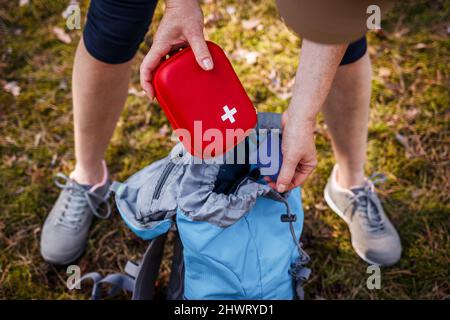 Woman taking out first aid kit from backpack. Prepared for health problems during hiking. Travel insurance for all eventualities Stock Photo