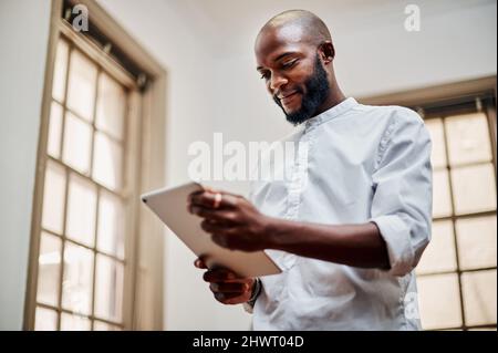 A great device for a designer like him. Shot of a young businessman using a digital tablet in a modern office. Stock Photo