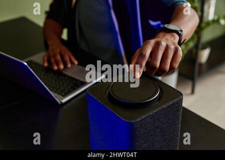 Close up of man operating smart speaker with home AI while working with laptop, copy space Stock Photo