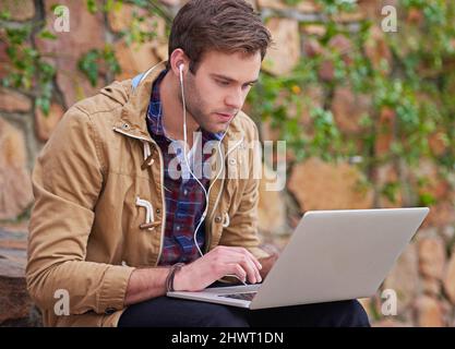 Hes a dedicated student. Shot of a handsome male student using his laptop on campus. Stock Photo