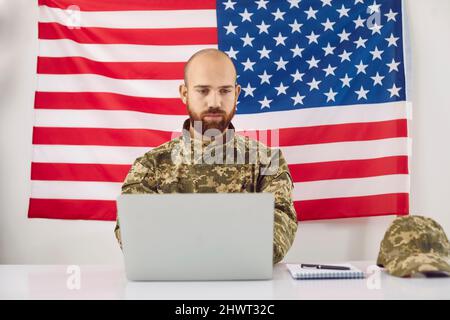American military student sitting at his desk and working on his laptop computer Stock Photo