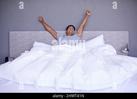 Best nights sleep ever. A young man stretching out while waking. Stock Photo