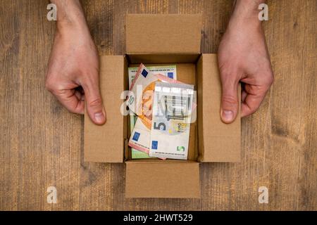 Euro banknotes in open box made from corrugated cardboard. Concept for donation, savings. Stock Photo