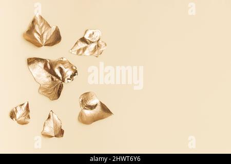 Creative gold background. Ivy leaves on sand color background. Minimal abstract golden composition. Copy space. Stock Photo