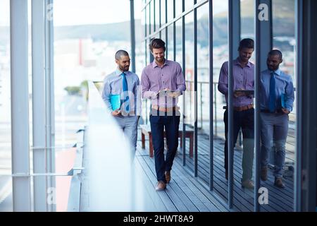 Meeting before their meeting. Shot of two young businessmen using a digital tablet together outside of an office building. Stock Photo