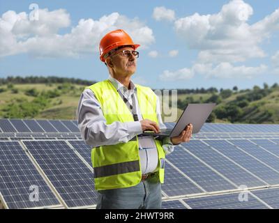Mature male engineer working with a laptop on a photovoltaic solar panel field Stock Photo