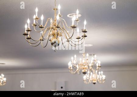 Several candelier lights hanging from a white ceiling to illuminate a room Stock Photo