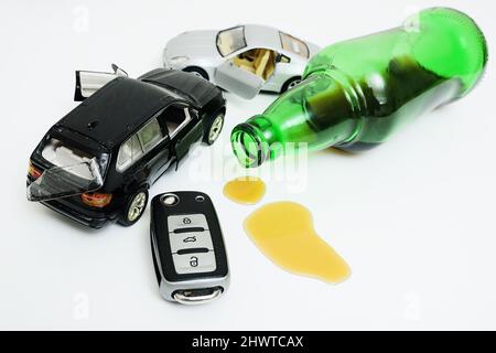 a broken toy car, a bottle with leftover alcohol and a car key on a white background. Stock Photo