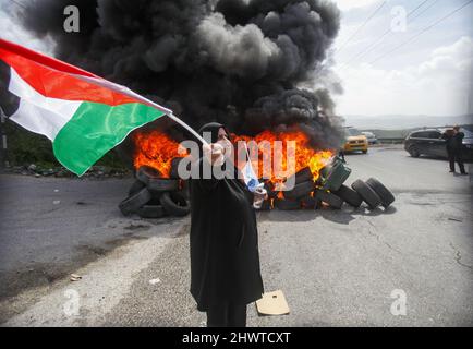 Gaza, Palestine. 07th Mar, 2022. A Palestinian woman holds the Palestinian flag during the protest. Ahead of International Women's Day, Palestinian women protested against the Israeli settlements and their expansion in the West Bank, near the Israeli settlement of Homesh in the occupied West Bank. Credit: SOPA Images Limited/Alamy Live News Stock Photo