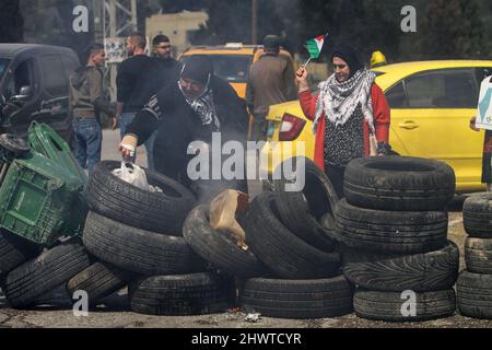 Gaza, Palestine. 07th Mar, 2022. A Palestinian woman burns tires during the protest. Ahead of International Women's Day, Palestinian women protested against the Israeli settlements and their expansion in the West Bank, near the Israeli settlement of Homesh in the occupied West Bank. Credit: SOPA Images Limited/Alamy Live News Stock Photo