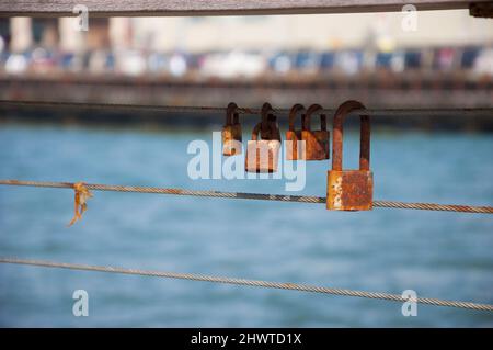 Rusty Love locks attached to railing in Tel Aviv port, Israel. Old love concept. Stock Photo