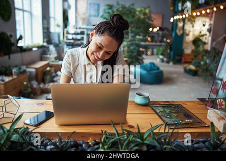 Joyful female florist working on her laptop Stock Photo