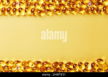 The texture of the capsules in the shell with liquid vitamin D3 in full screen. Gold capsules with a dietary supplement for joints teeth and bones. Stock Photo