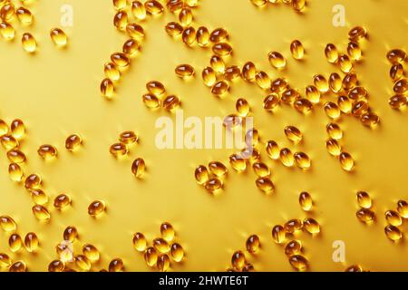 The texture of the capsules in the shell with liquid vitamin D3 in full screen. Gold capsules with a dietary supplement for joints teeth and bones. Stock Photo