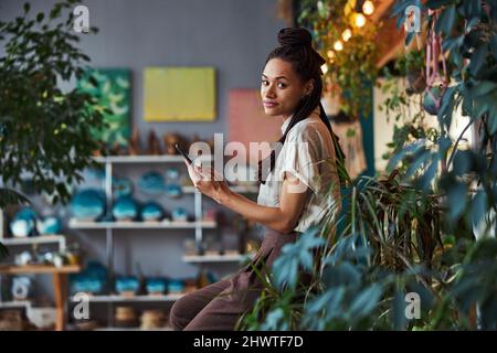 Tranquil floral designer using her cellphone at work Stock Photo