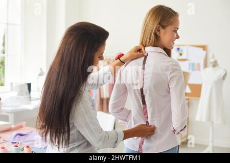 Dressmaker measure client with tape in fashion atelier Stock Photo