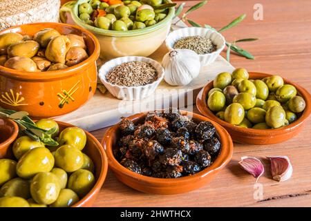 Still life with different varieties of olives, presented in bowls, dressed with different traditional dressings. Traditional homemade dressings, typic Stock Photo