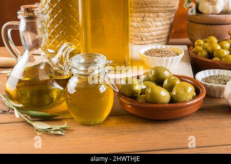 Still life with different varieties of olives seasoned in the traditional way, presented in bowls on wooden boards, and extra virgin olive oil in seve Stock Photo