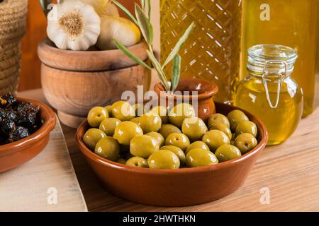 Still life with different varieties of olives seasoned in the traditional way, presented in bowls on wooden boards, and extra virgin olive oil in seve Stock Photo