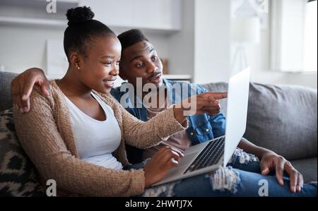 Check out this offer. Shot of a young couple using a laptop together on a sofa at home. Stock Photo