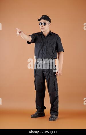 Serious security officer in cap and sunglasses pointing with index finger Stock Photo