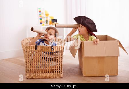 Whats that over there. Shot of two little boys pretending to be pirates in their bedroom. Stock Photo