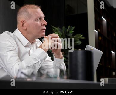 Thoughtful smart businessman sitting at office desk and thinking of future plans, ideas, problems, strategy, new chances. High quality photo Stock Photo