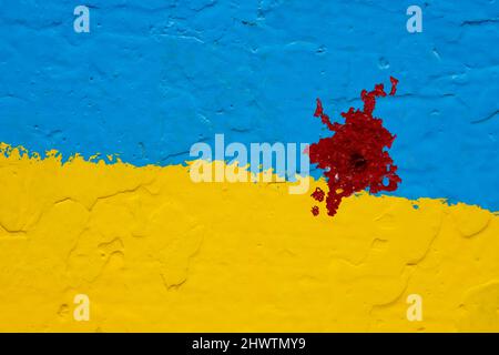 concrete wall painted in yellow and blue like Ukrainian flag with a bloody red stain from a bullet Stock Photo