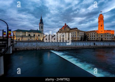 Sunrise orange light over the Oradea city hall tower and building against a cloudy sky. Photo taken on 19th February 2022 in Oradea, Bihor County, Tra Stock Photo