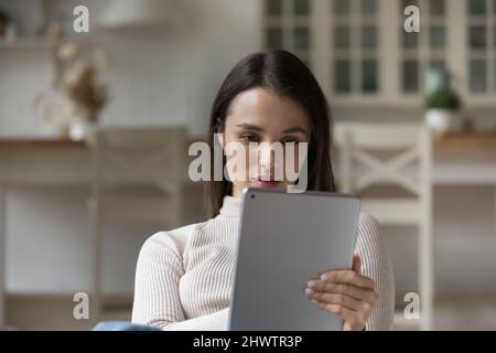 Attractive serious woman spend leisure at home using digital tablet Stock Photo