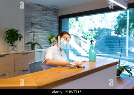 Young woman cleaning reception of spa center Stock Photo