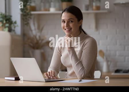 Woman sit at table with laptop smile look at camera Stock Photo