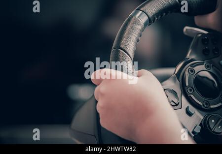 Technology, gaming, entertainment and people concept - young man playing car racing video game at home and steering wheel. Stock Photo