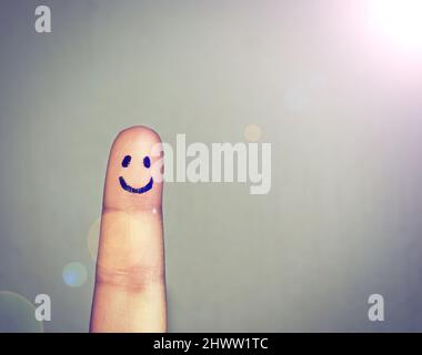 Get your happy face on. Shot of a finger with a happy face drawn on it. Stock Photo