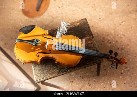 Violin with feather resting on stool Stock Photo