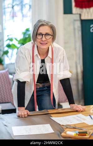 Woman with measure standing near table with sketches Stock Photo
