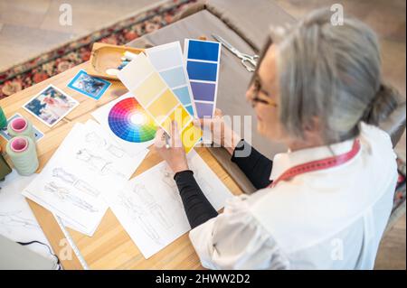 Woman sitting at table holding color palettes Stock Photo