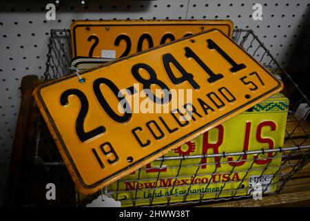 A selection of vintage automobile licernse plates for sale, including a 1957 plate from Colorado, for sale in an antique shop. Stock Photo