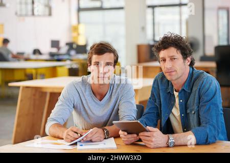 Partners in design. Shot of two coworkers using a digital tablet together in an office. Stock Photo