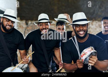 Playing together in sync to the beat. Portrait of a group of musical performers playing together indoors. Stock Photo
