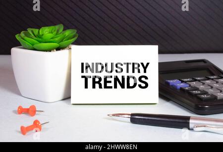 INDUSTRY TRENDS text on paper with calculator, notepad, coffee ,pen with graph. Stock Photo