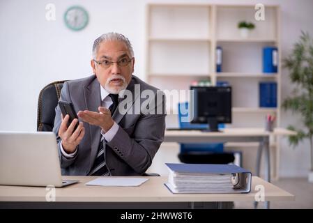 Aged male employee sitting at workplace Stock Photo