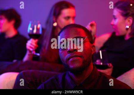 Close up of African American man wearing colored sunglasses at party lit by neon lights Stock Photo