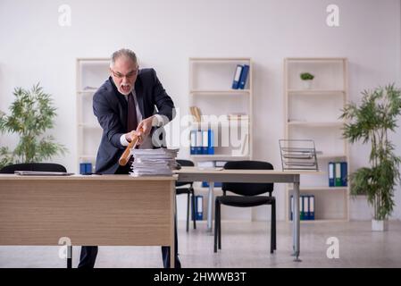 Old businessman employee unhappy with excessive work in the office Stock Photo