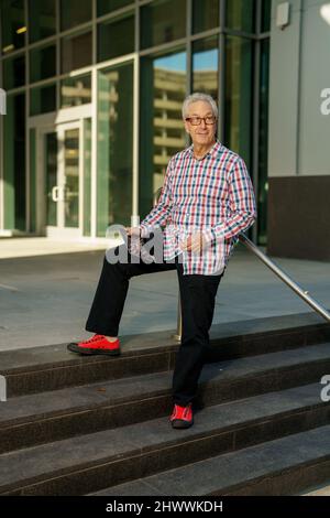 Businessman with digital tablet in hand smiling away from camera Stock Photo