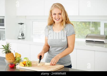 Nothing beats fresh fruit. Attractive curvaceous young woman chopping fruit in her kitchen. Stock Photo